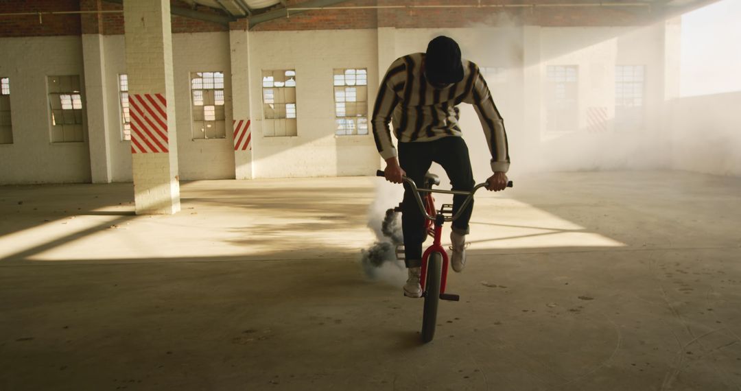 BMX rider practicing stunts in empty warehouse with smoke effect - Free Images, Stock Photos and Pictures on Pikwizard.com