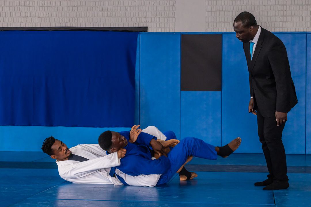 African American Grapplers in Intense Jiu-Jitsu Contest with Referee Overseeing