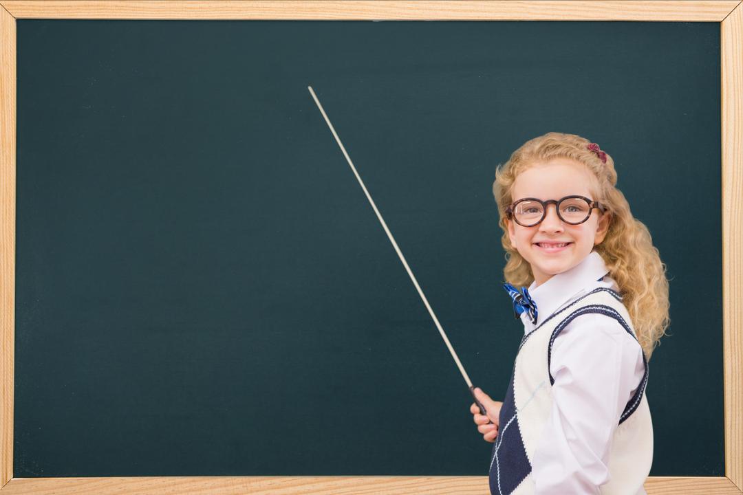 Side view of smiling schoolgirl with stick standing by blackboard - Free Images, Stock Photos and Pictures on Pikwizard.com