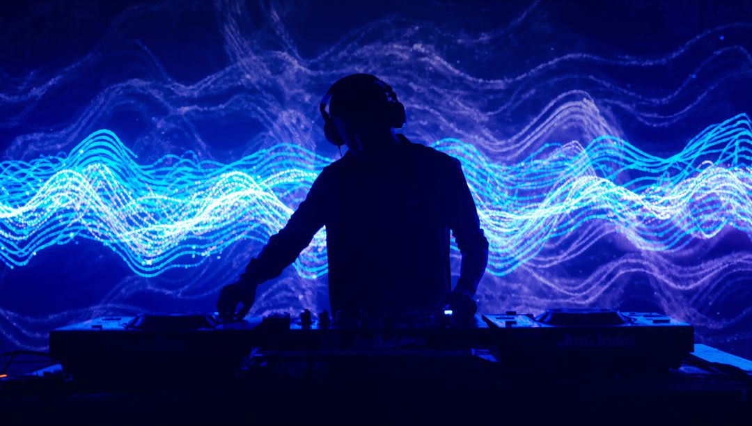 Mixing DJ Silhouette Performing Behind Neon Waveform Visuals with Headphones and Mixer