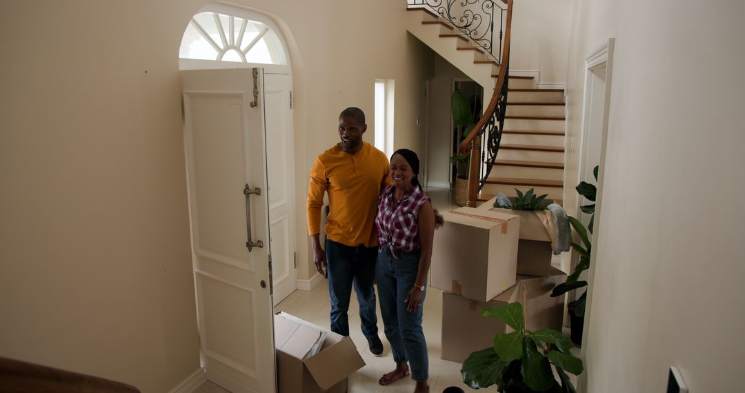 Couple Moving Into New Home with Cardboard Boxes and Smiles