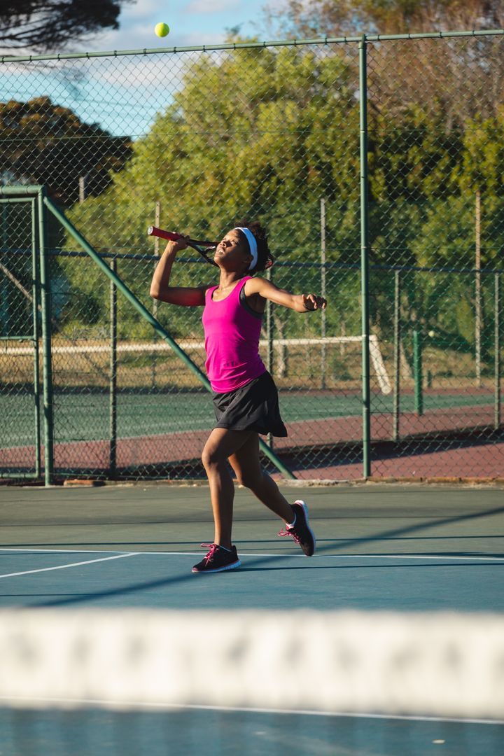 Full length of young female african american tennis player serving at court on sunny day - Free Images, Stock Photos and Pictures on Pikwizard.com