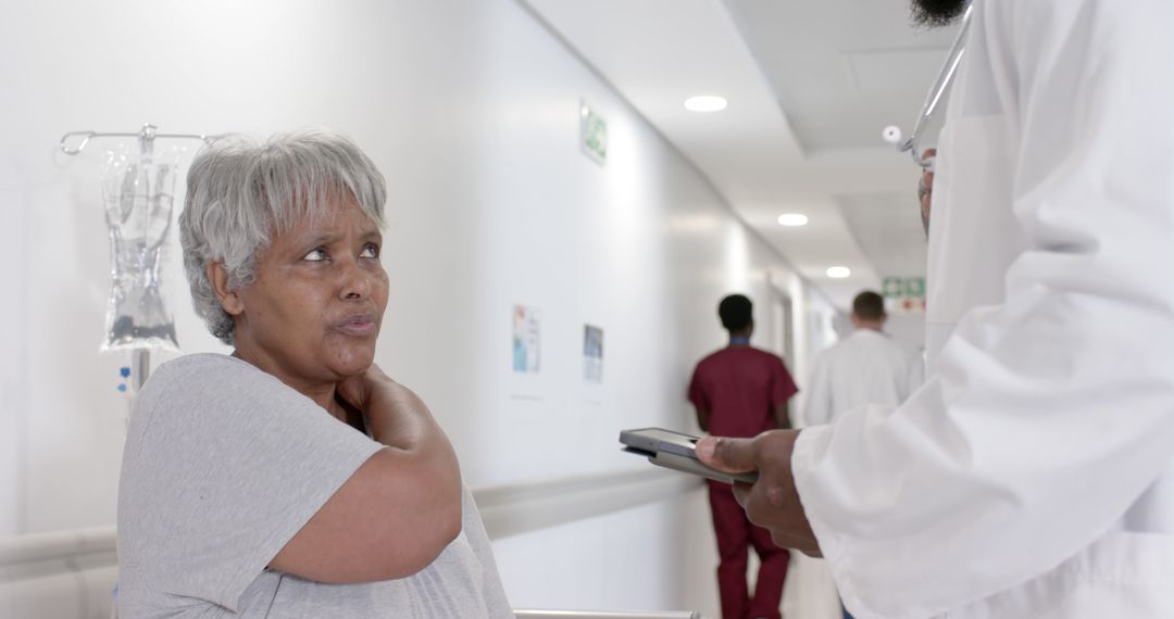 Elderly Woman Speaking with Doctor in Hospital Hallway - Free Images, Stock Photos and Pictures on Pikwizard.com