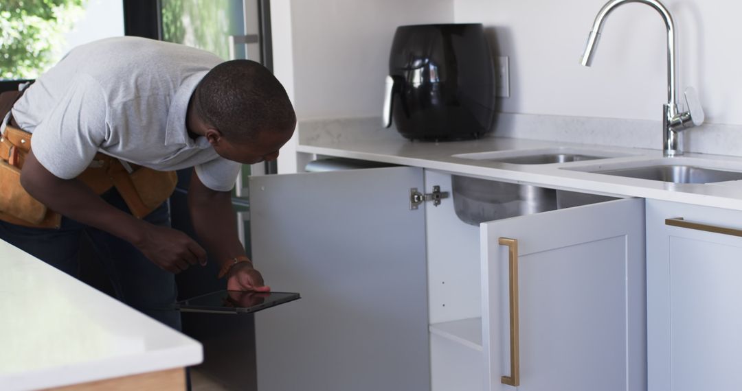 Plumber Using Tablet for Kitchen Repair Guidance
