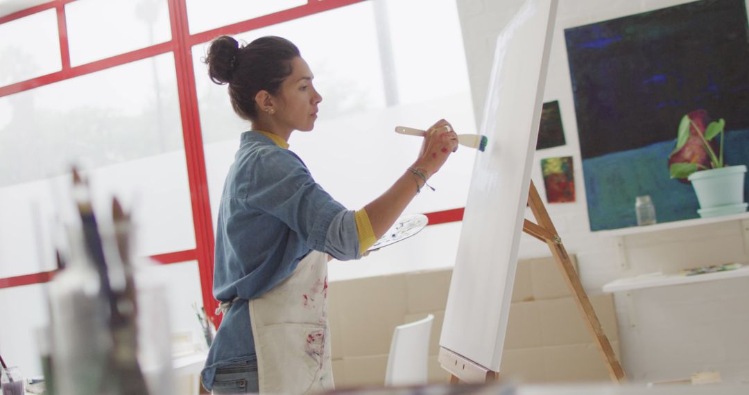 Image of biracial female artist painting in studio - Free Images, Stock Photos and Pictures on Pikwizard.com