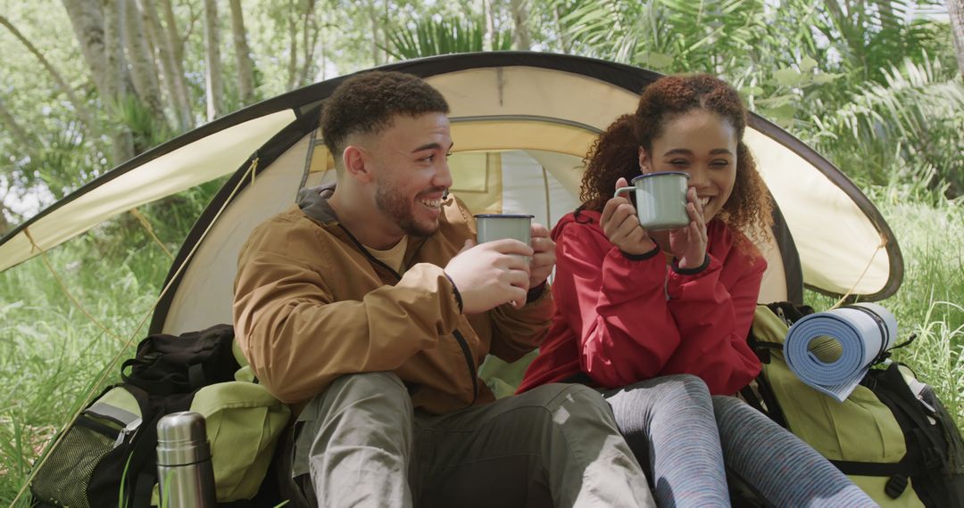 Happy Mixed Ethnicity Couple Camping in Forest Enjoying Hot Drinks - Free Images, Stock Photos and Pictures on Pikwizard.com