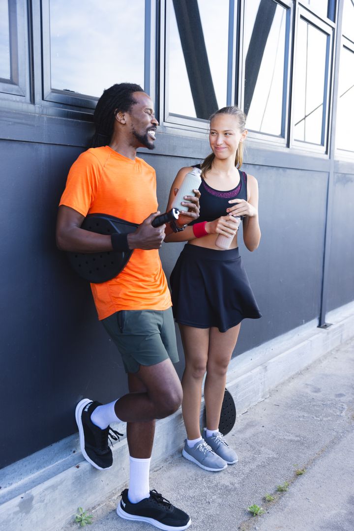 Diverse Friends Taking Break After Padel Game with Equipment and Refreshments