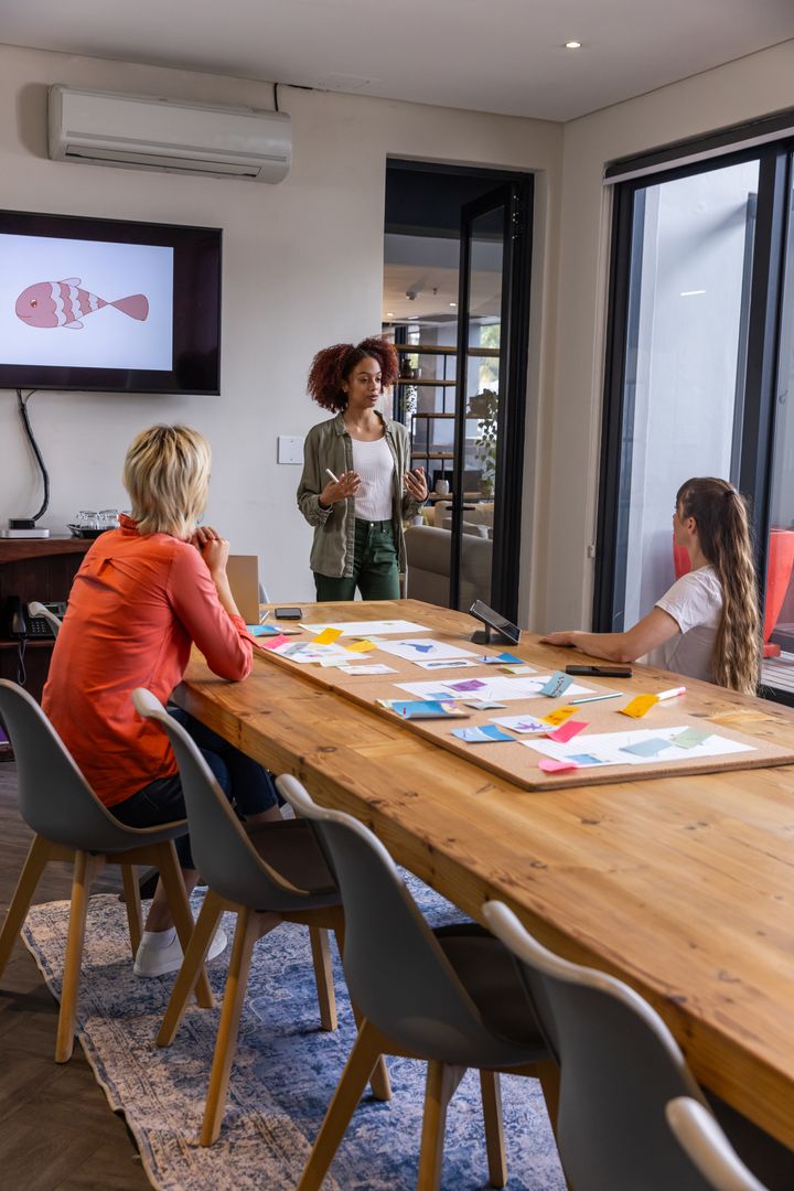 Diverse Team Collaborating with Sticky Notes and Mockups in Meeting Room