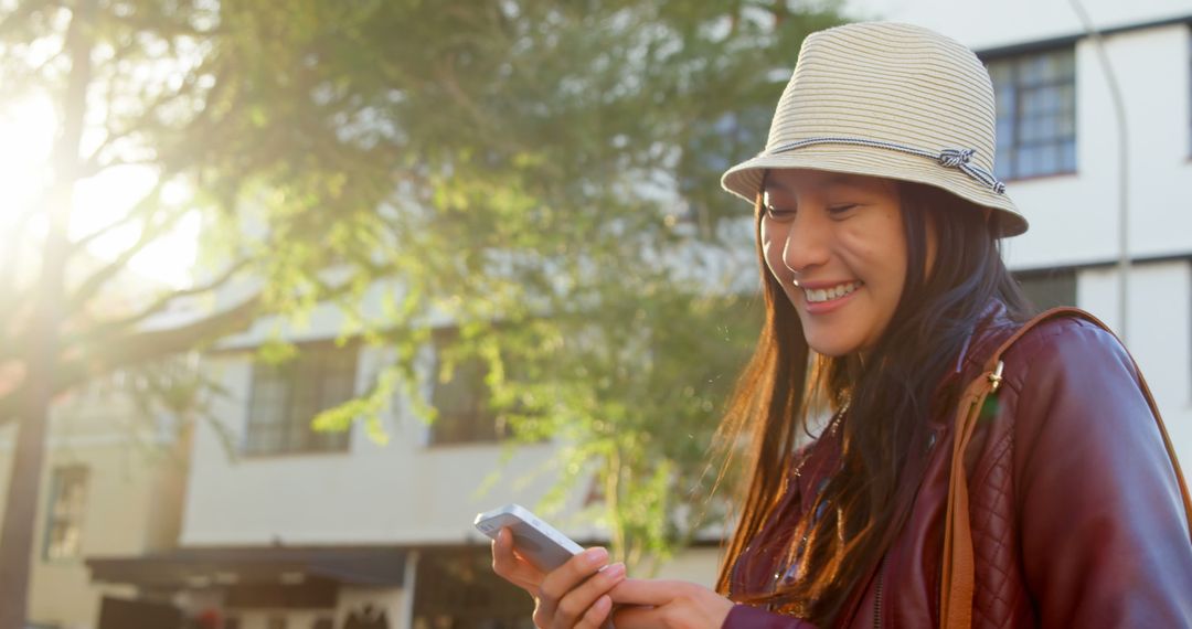 Smiling Woman Using Smartphone Outdoors on Sunny Day - Free Images, Stock Photos and Pictures on Pikwizard.com