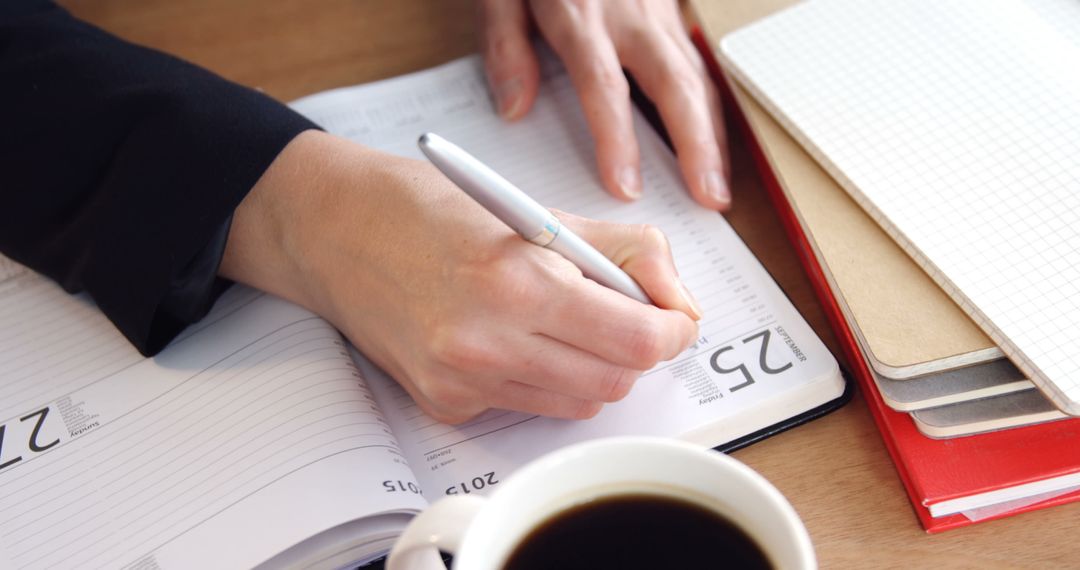 Person Writing in Planner with Coffee on Desk - Free Images, Stock Photos and Pictures on Pikwizard.com