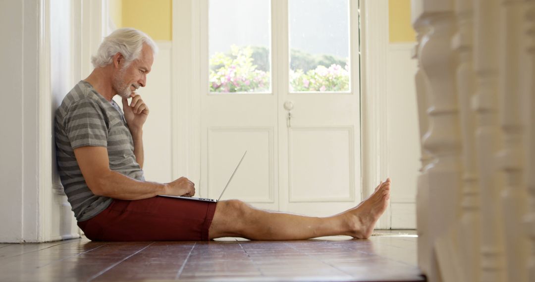 Senior Man Sitting on Floor Using Laptop at Home - Free Images, Stock Photos and Pictures on Pikwizard.com