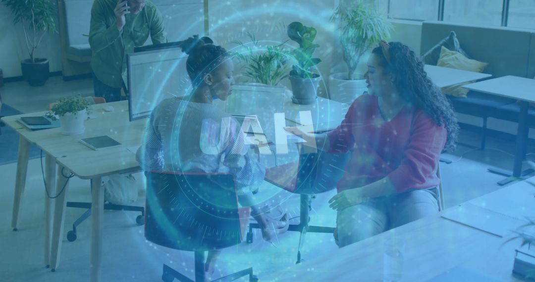 Women Collaborating with UAH Technology Overlay in Modern Office
