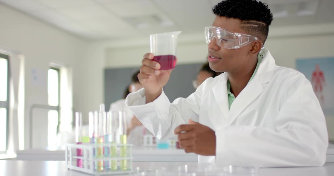 Teen scientist examining purple solution in school lab wearing protective goggles