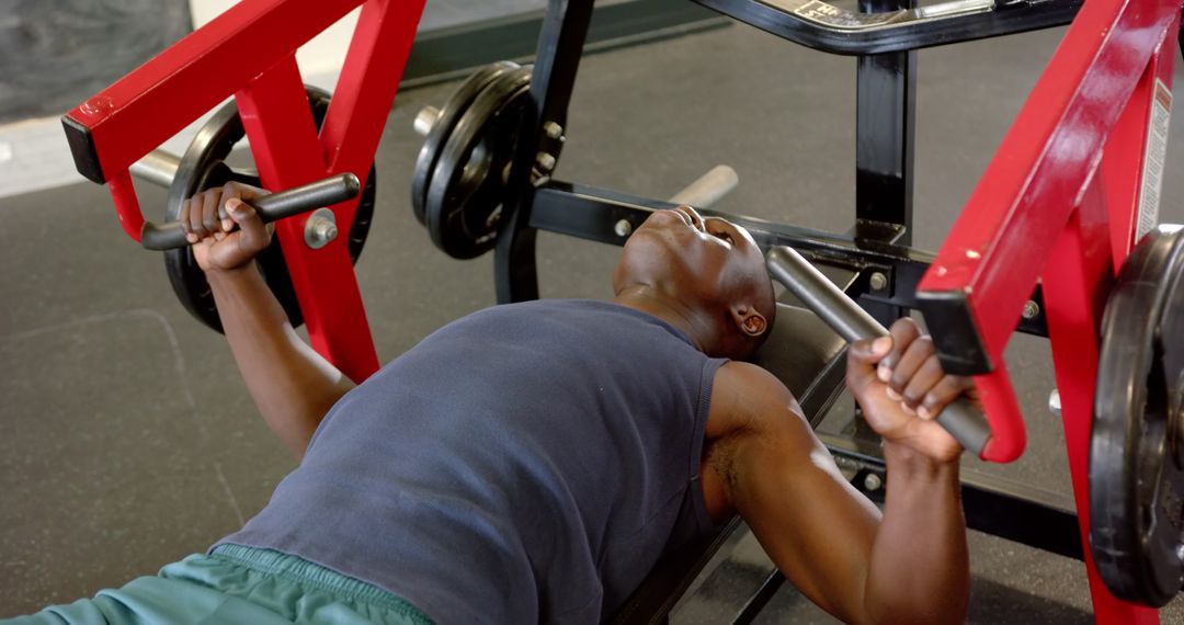 Athletic Man Lifting Weights on Bench Press Machine at Gym