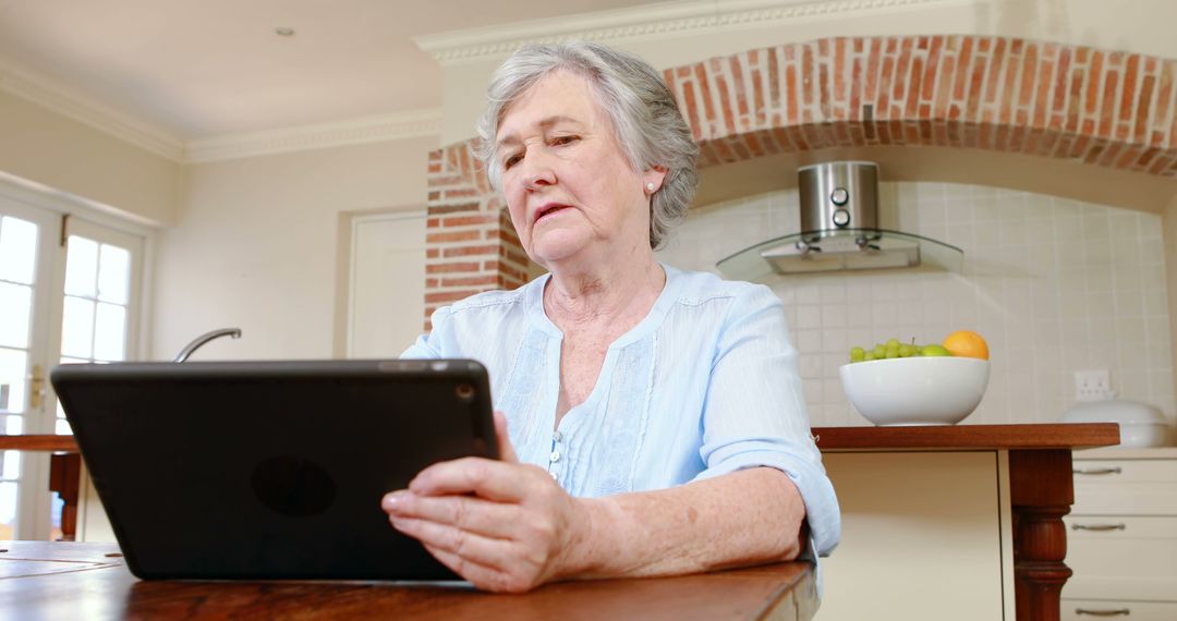 Elderly Woman Using Tablet in Modern Kitchen - Free Images, Stock Photos and Pictures on Pikwizard.com