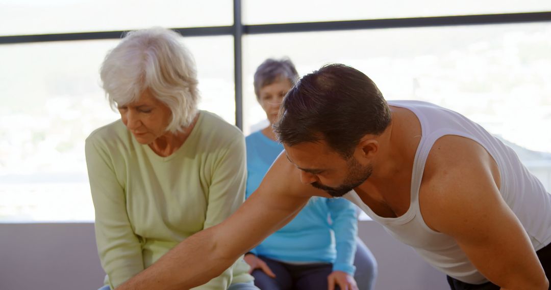 Instructor Helping Senior with Yoga Stretch in Class - Free Images, Stock Photos and Pictures on Pikwizard.com