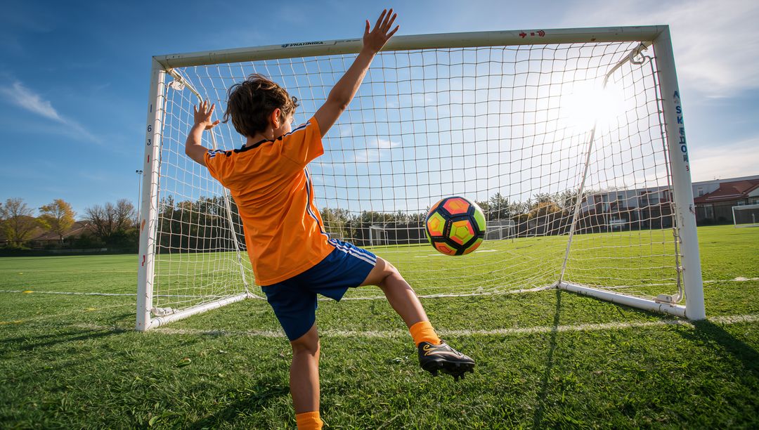 Youth Soccer Player Blocking Goal on Sunny Field