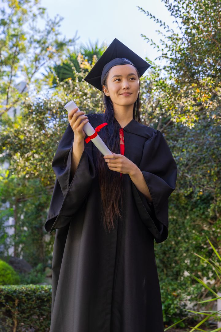 Elegant Graduate Holding Diploma in Tranquil Garden