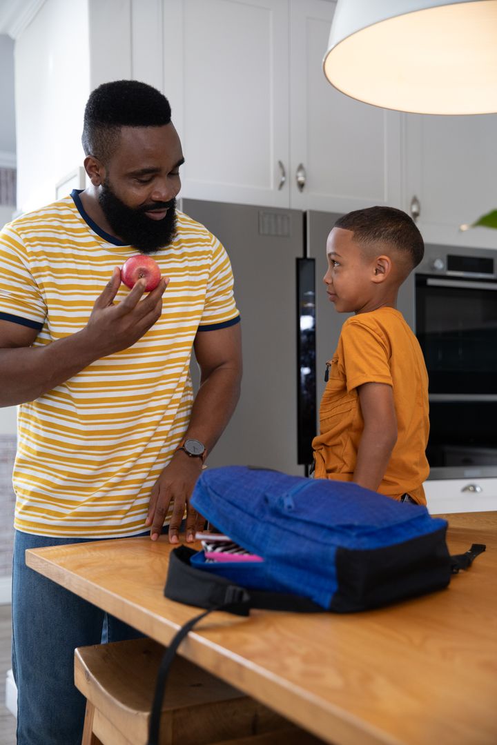 Father and Son Preparing for School in Kitchen