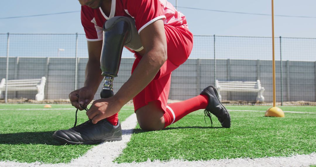 Disabled soccer player tying shoe on the field in sportswear - Free Images, Stock Photos and Pictures on Pikwizard.com