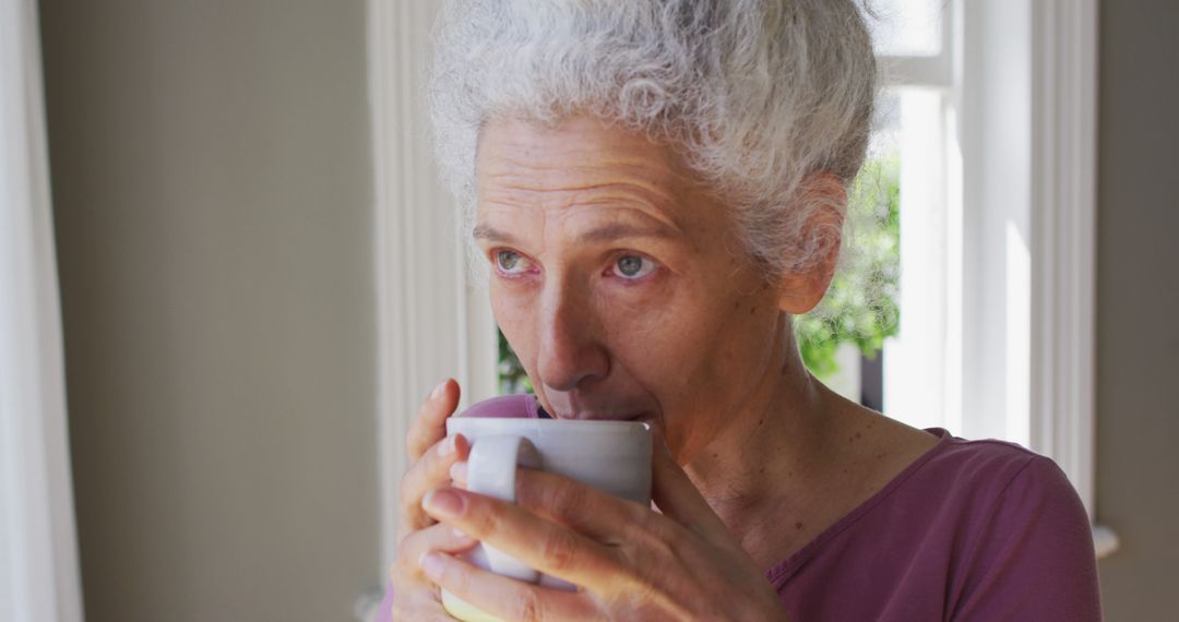 Senior Woman Drinking Hot Beverage by Window - Free Images, Stock Photos and Pictures on Pikwizard.com