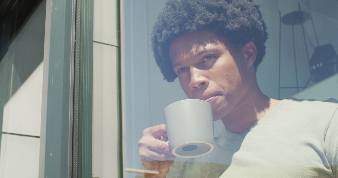 Man with Afro Hair Drinking Coffee by Window Enjoying Leisure Time