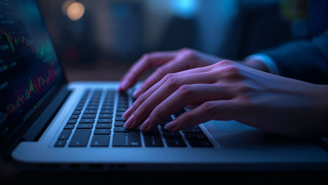 Professional Hands Typing on Laptop with Financial Charts