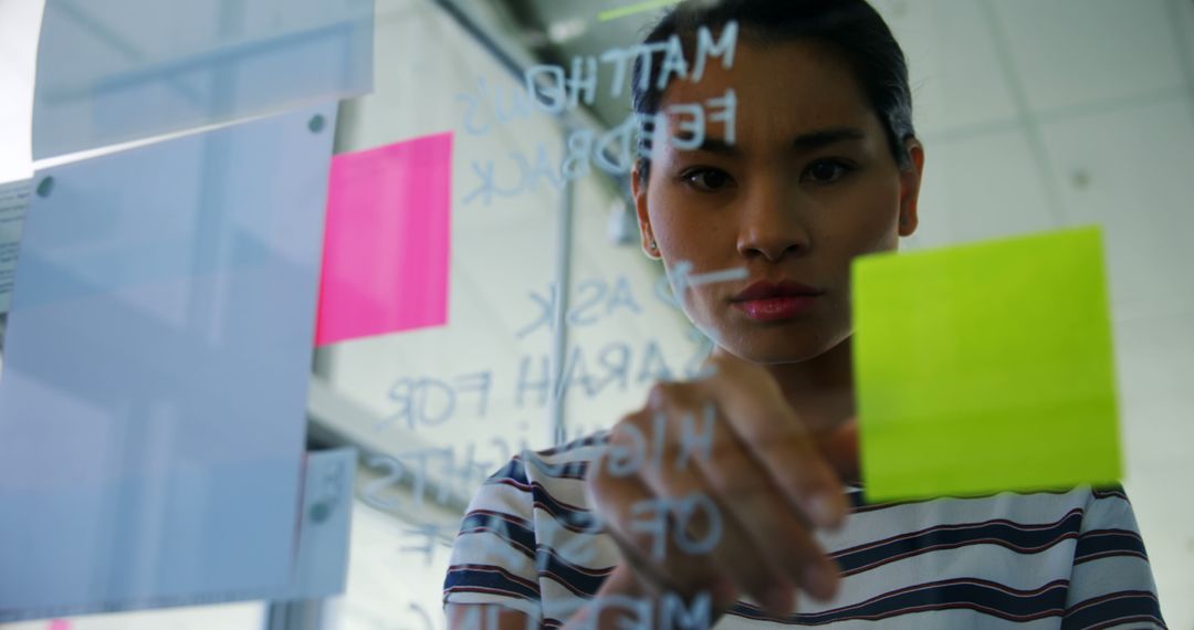 Focused Businesswoman Planning Strategy With Sticky Notes on Glass Wall - Free Images, Stock Photos and Pictures on Pikwizard.com