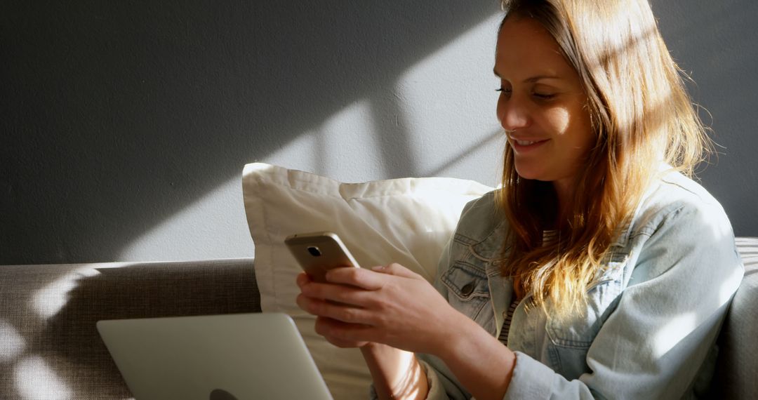 Woman Sitting on Couch Using Smartphone Smiling - Free Images, Stock Photos and Pictures on Pikwizard.com