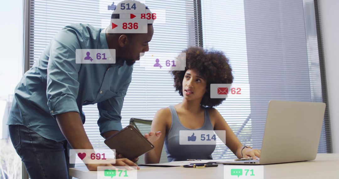 Collaborating over laptop and tablet while analyzing social media metrics in bright office