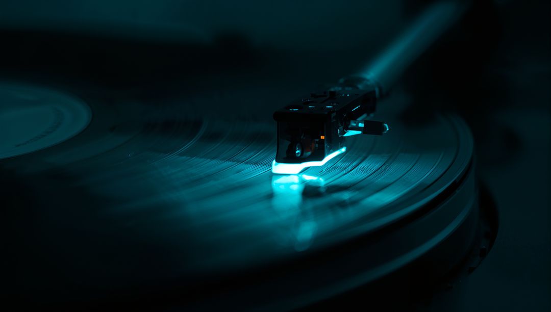 Glowing Stylus Tracing Spinning Vinyl Record on Turntable with Moody Teal Blue Lighting