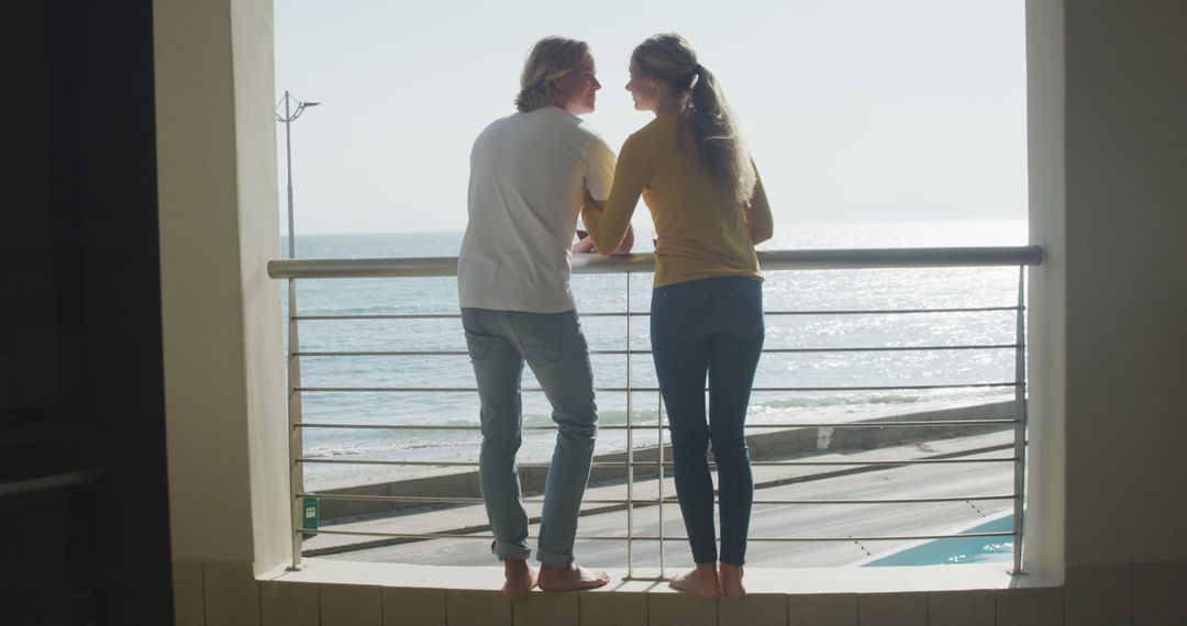 Young Couple Standing on Balcony Enjoying Ocean View - Free Images, Stock Photos and Pictures on Pikwizard.com