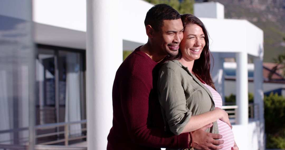 Diverse Couple Embracing Pregnancy on Balcony with Modern Feel