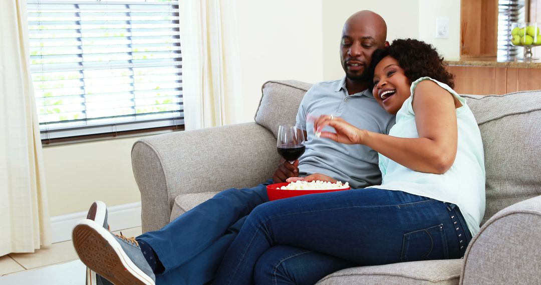 Happy Couple Relaxing with Wine and Popcorn on Sofa