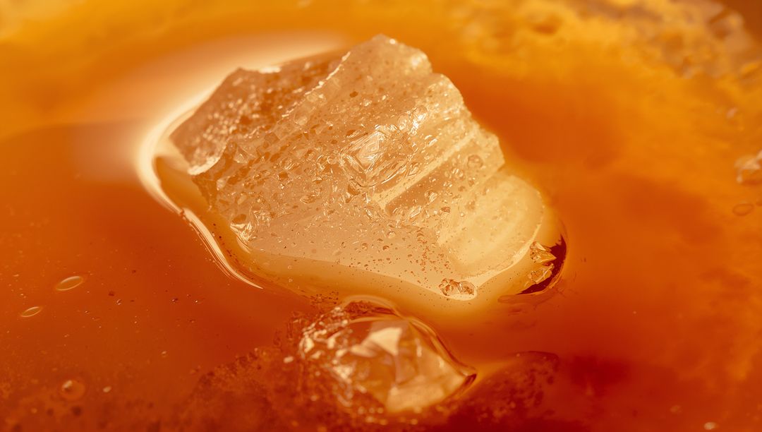 Crystal Chunk Resting in Amber Syrup Macro Close-Up Showing Glistening Translucent Texture