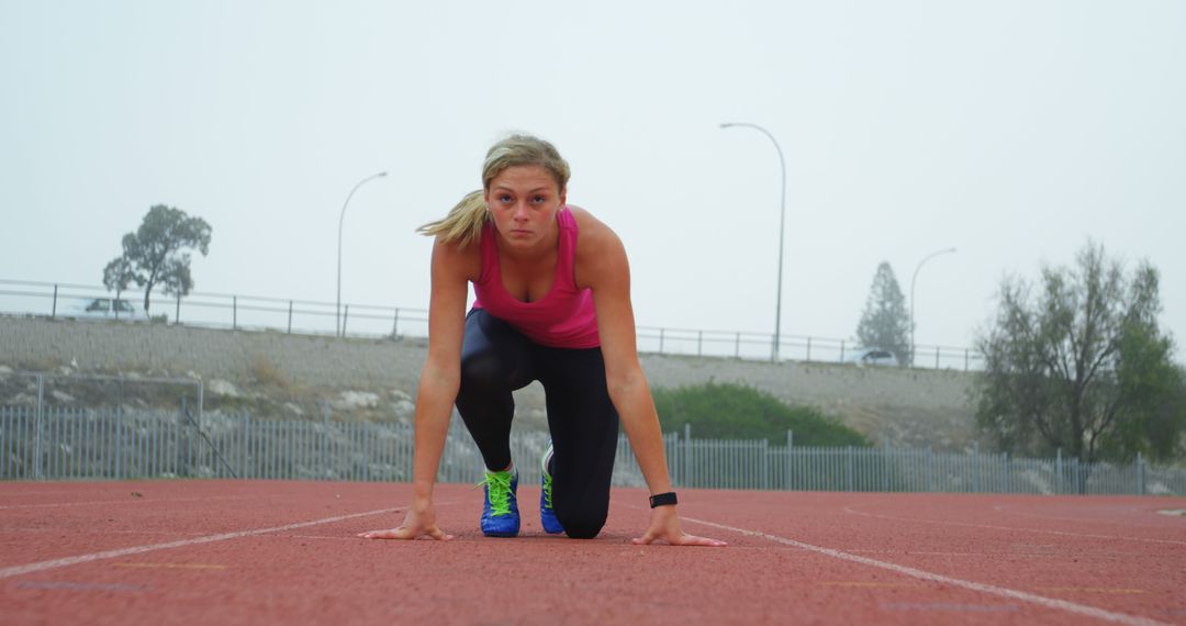 Female Athlete in Starting Position on Track Ready to Race