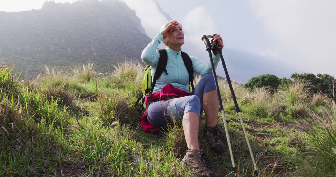 Senior Woman Taking Rest While Hiking in Mountain Terrain - Free Images, Stock Photos and Pictures on Pikwizard.com