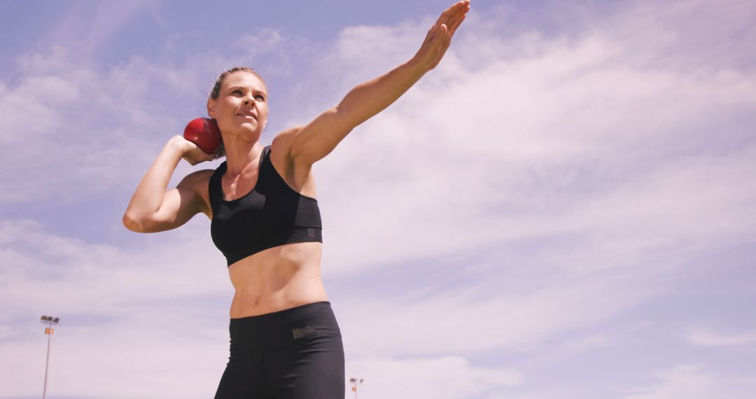 Female Athlete Practicing Shot Put Outdoors Under Blue Sky - Free Images, Stock Photos and Pictures on Pikwizard.com