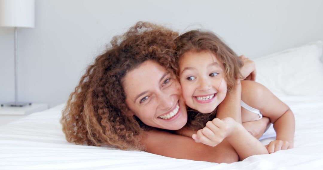 Happy Mother Cuddling Her Smiling Daughter on Bed - Free Images, Stock Photos and Pictures on Pikwizard.com