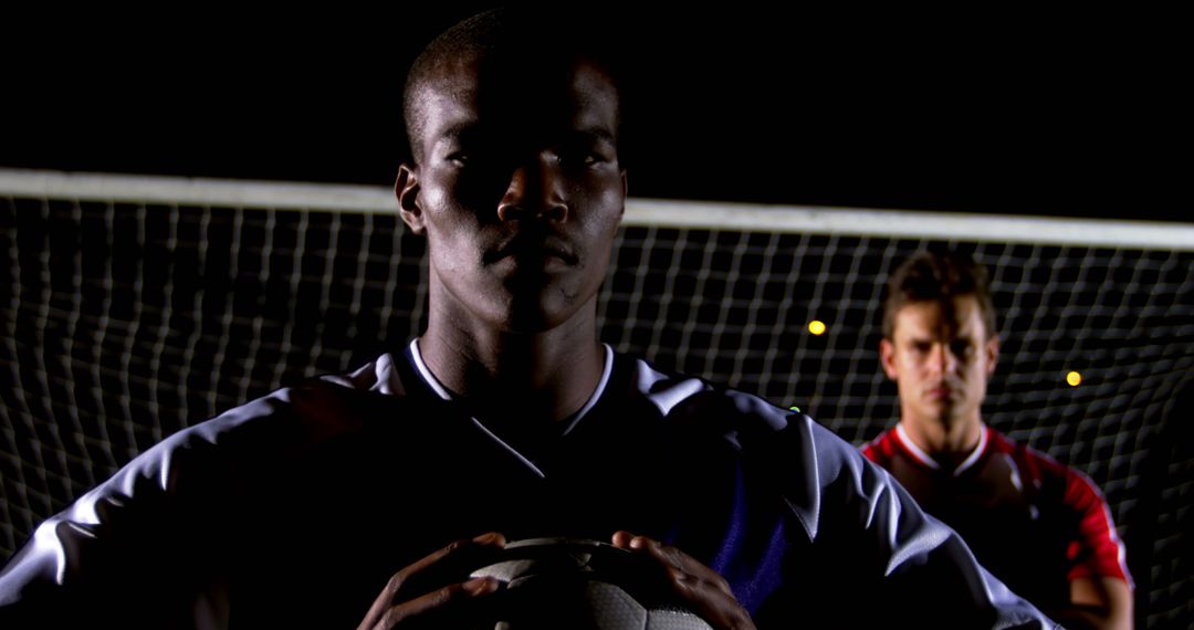 Confident Soccer Player Holding Ball with Teammate, Night Game - Free Images, Stock Photos and Pictures on Pikwizard.com