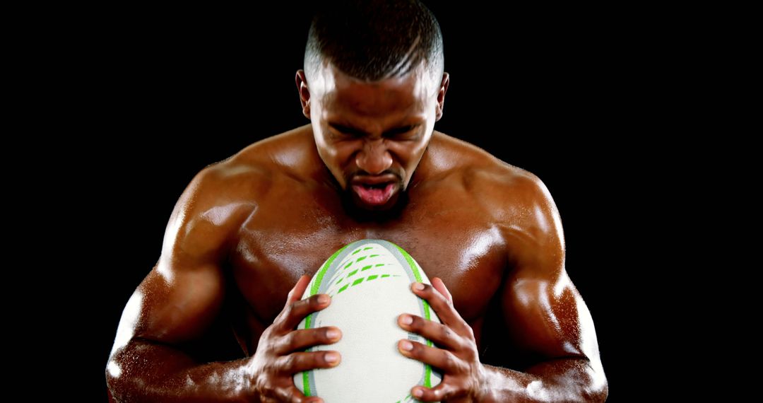 Muscular Athlete Holding Rugby Ball Focused Intense Expression - Free Images, Stock Photos and Pictures on Pikwizard.com