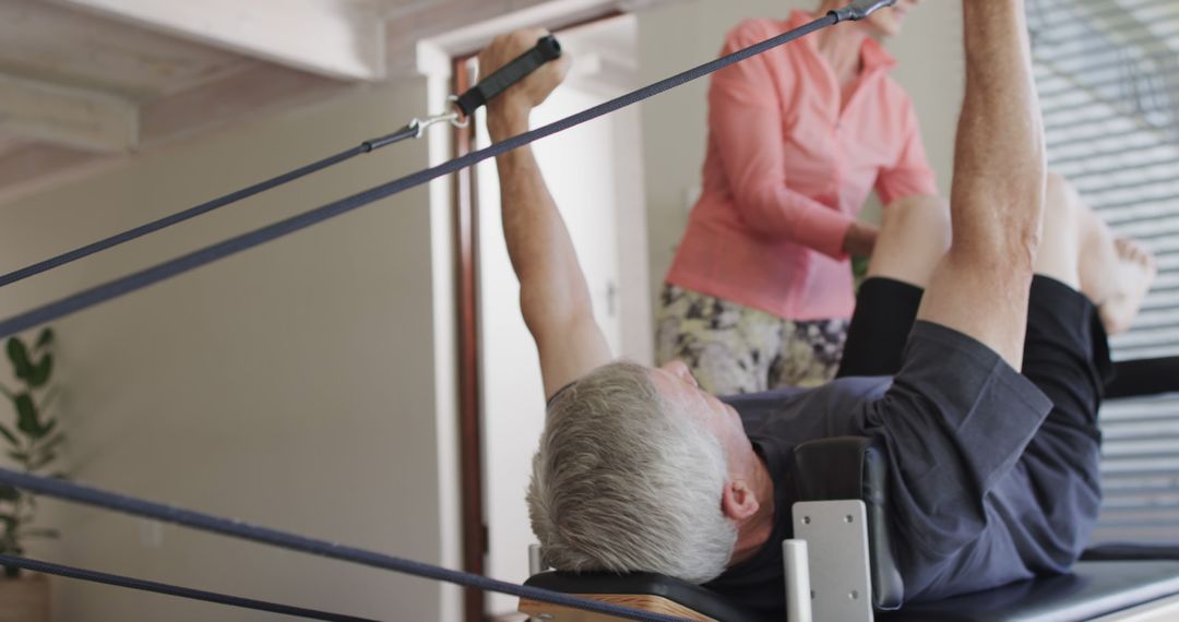 Senior Man Exercising on Pilates Reformer with Trainer's Assistance - Free Images, Stock Photos and Pictures on Pikwizard.com