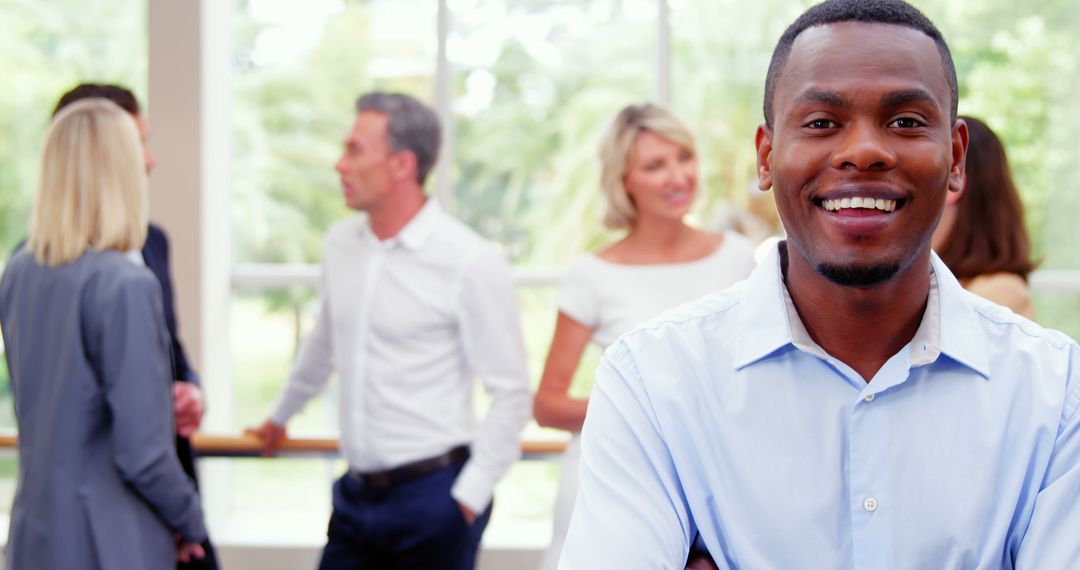 Confident Black Businessman Smiling in Office with Colleagues in Background - Free Images, Stock Photos and Pictures on Pikwizard.com