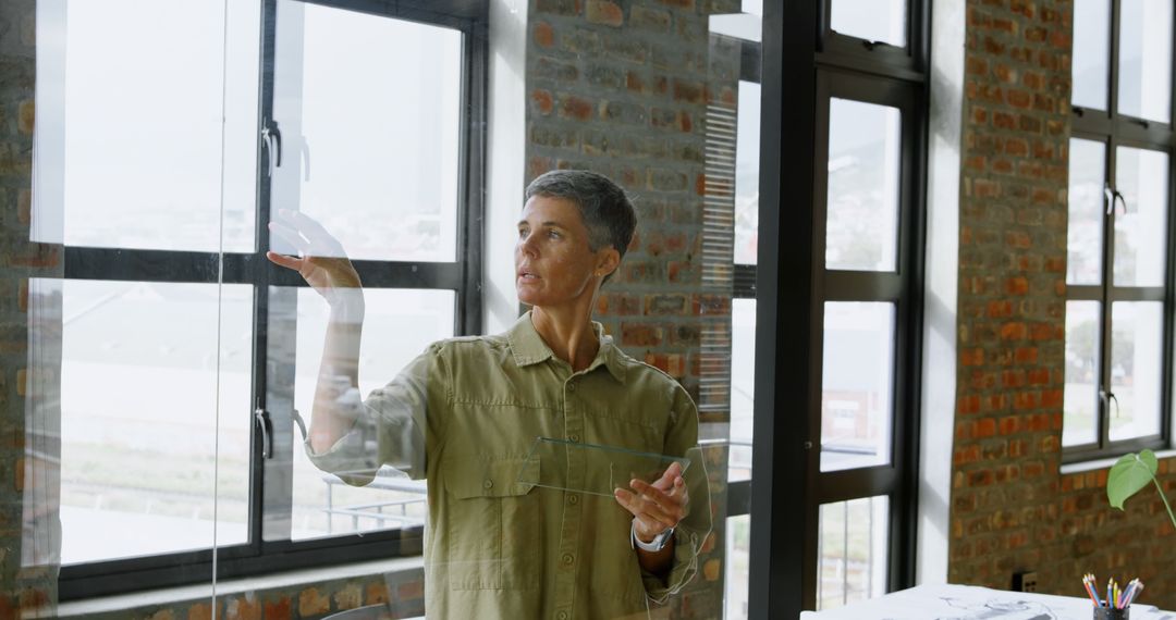 Woman Examining Windowpanes in Modern Office - Free Images, Stock Photos and Pictures on Pikwizard.com