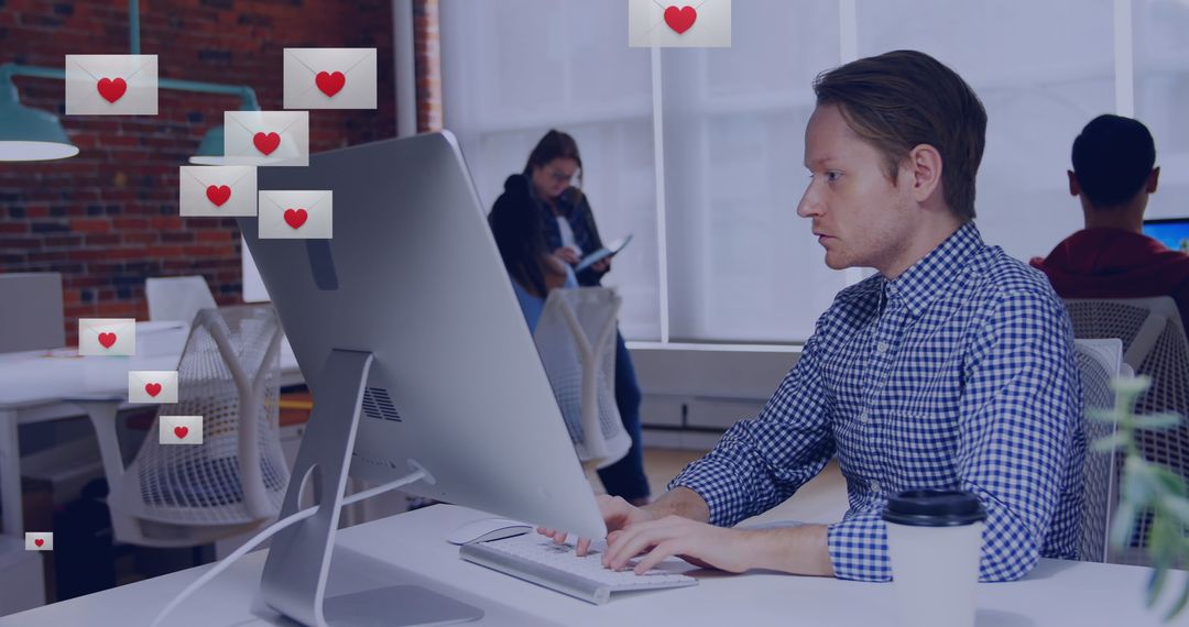 Heart Emojis Hovering Over Man Typing on Desktop in Shared Office