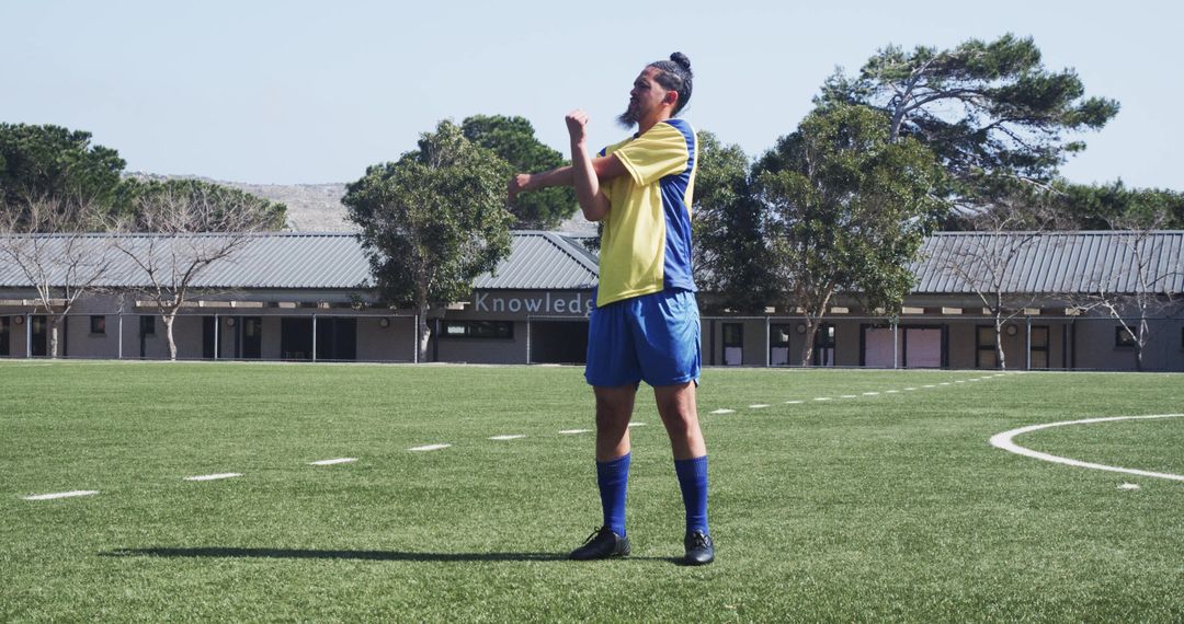 Soccer Player Stretching on Field Preparing for Practice