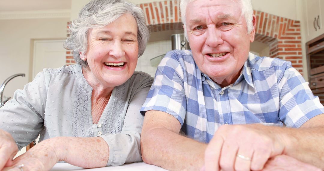 Joyful Senior Couple Sitting and Smiling in Rustic Kitchen - Free Images, Stock Photos and Pictures on Pikwizard.com