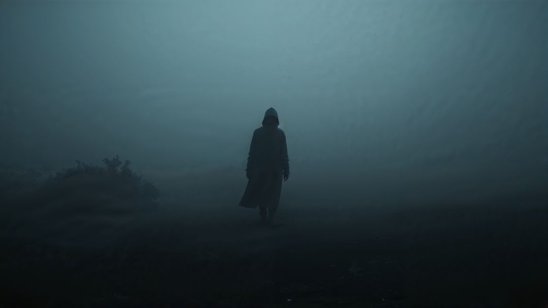 Mysterious Hooded Figure Walking Through Foggy Wilderness