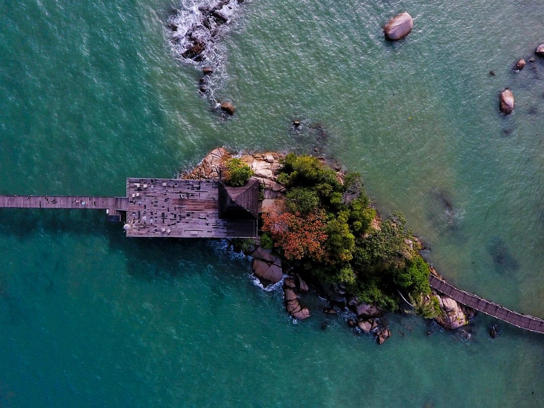 Aerial View of Wooden Pier and Small Island with Lush Vegetation - Free Images, Stock Photos and Pictures on Pikwizard.com