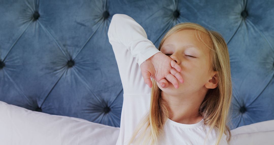 Tired Child Yawning on Bed with Blue Velvet Headboard - Free Images, Stock Photos and Pictures on Pikwizard.com